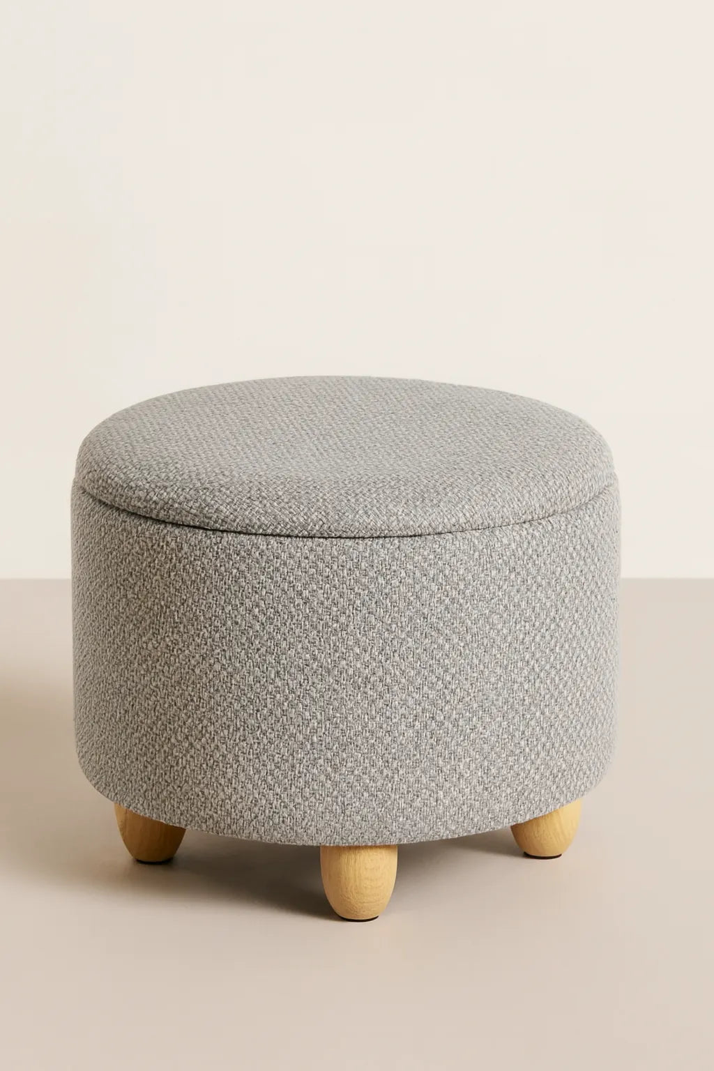 Gray textured ottoman with wooden legs on a beige background