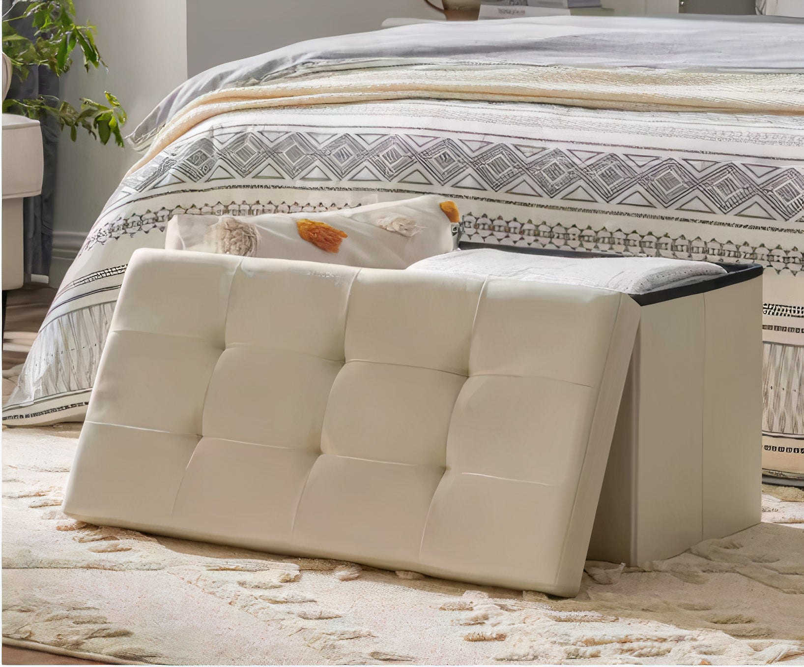 White upholstered bench in front of a bed with patterned bedding.