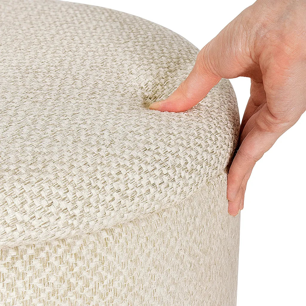 Hand pressing into a textured beige ottoman on a white background