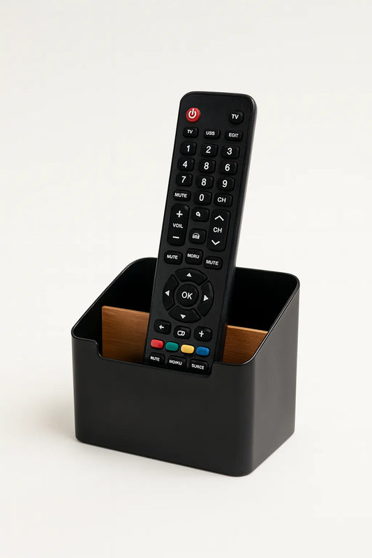 Black remote control in a rectangular black container on a white background