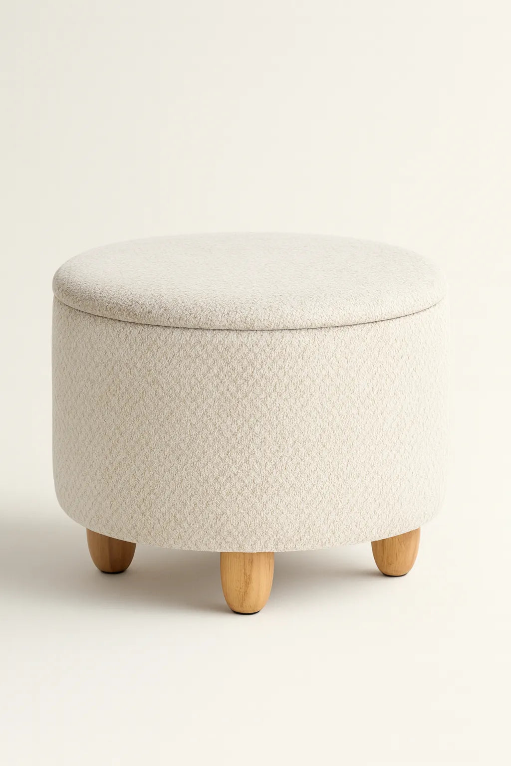Round ottoman with a textured beige cover and wooden legs on a white background